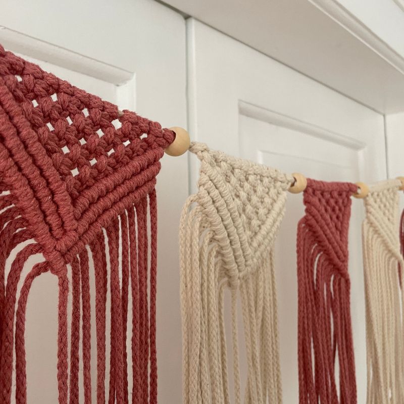 Makramee Girlande in rosa und creme vor weißer Wand aus dem DIY Makramee Set von Noué