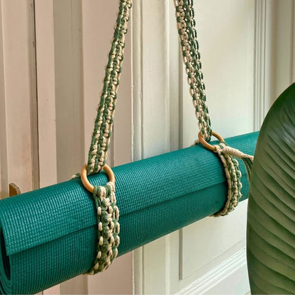 grüne Yogamatte mit Makramee Ygamattengurt vor weißer Wand