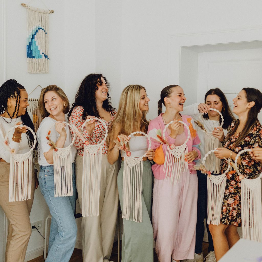 Gruppe von lachenden Frauen beim JGA mit Makramee Kranz in den Händen