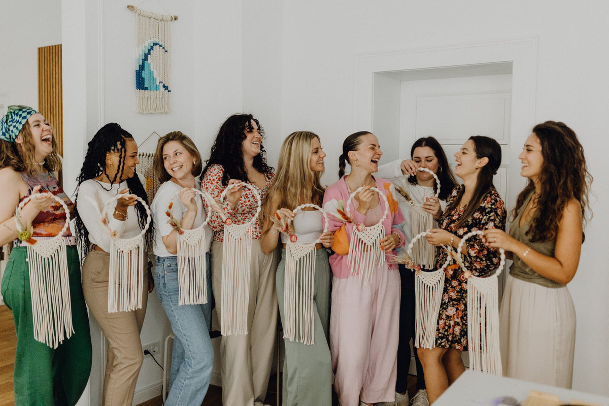 Lachende Frauen bei Makramee Workshop mit ihren Makramee Kränzen mit Trockenblumen