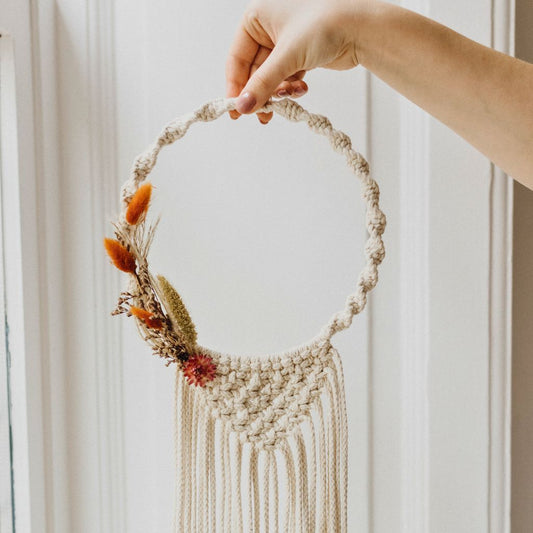 Makramee Kranz mit Trockenblumen vor weißer Wand