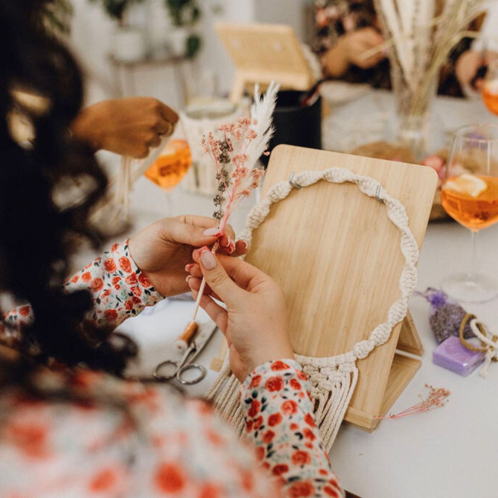 Frau sucht Trockenblumen für ihren Makramee Kranz aus. Beim Makramee Workshop von Noué