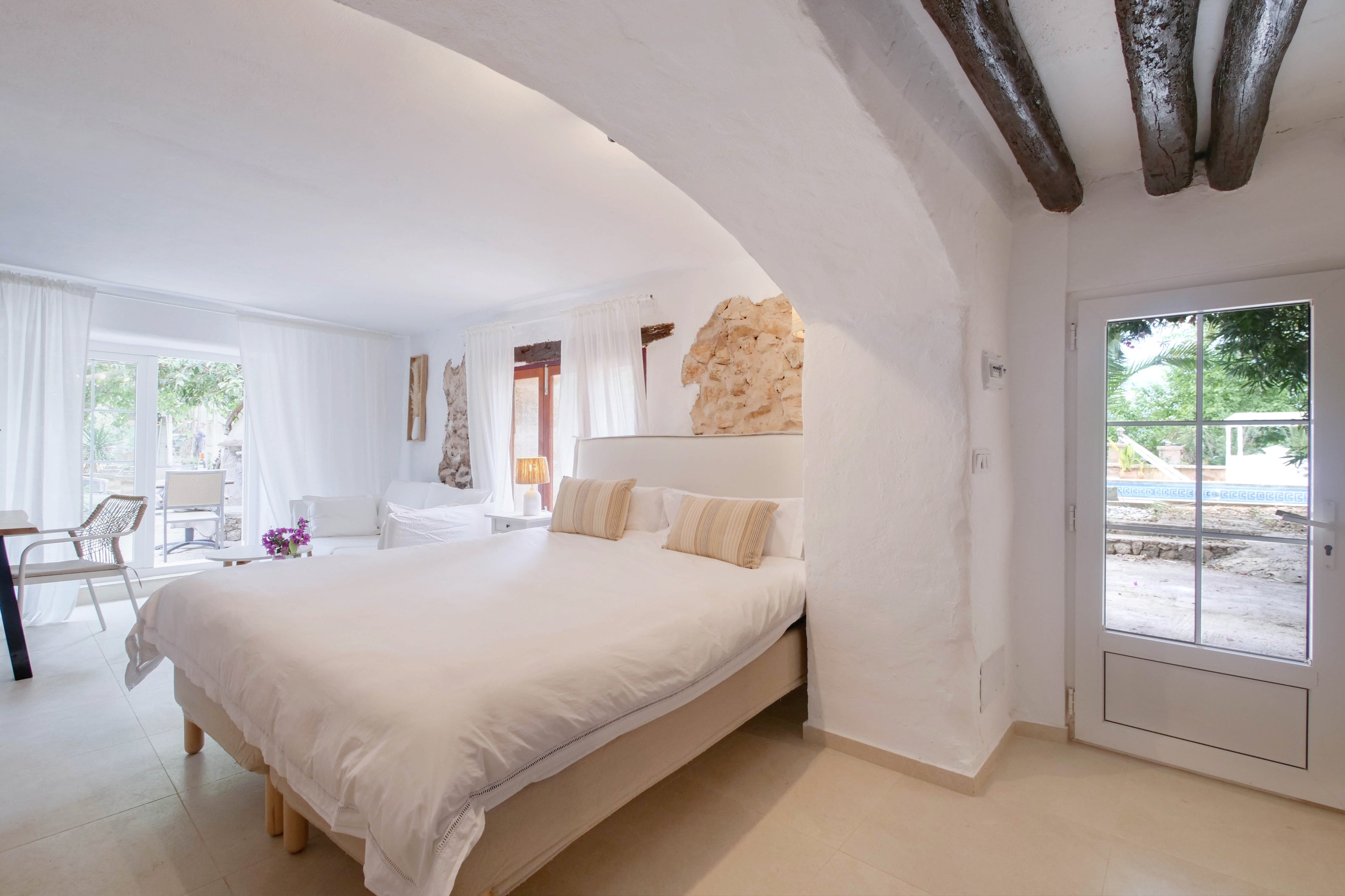 Helles Doppelzimmer mit weißem Bett im Retreat Hotel Finca Zenara auf Mallorca